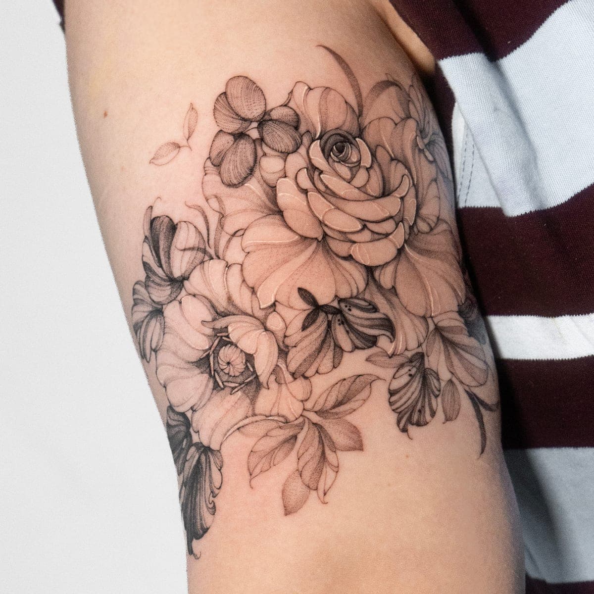 Fresh black and grey flowers with a rose on the back of an arm