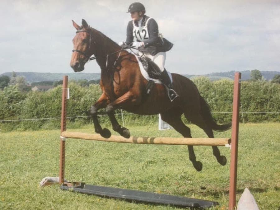 Boo clearing a jump in a field with her rider